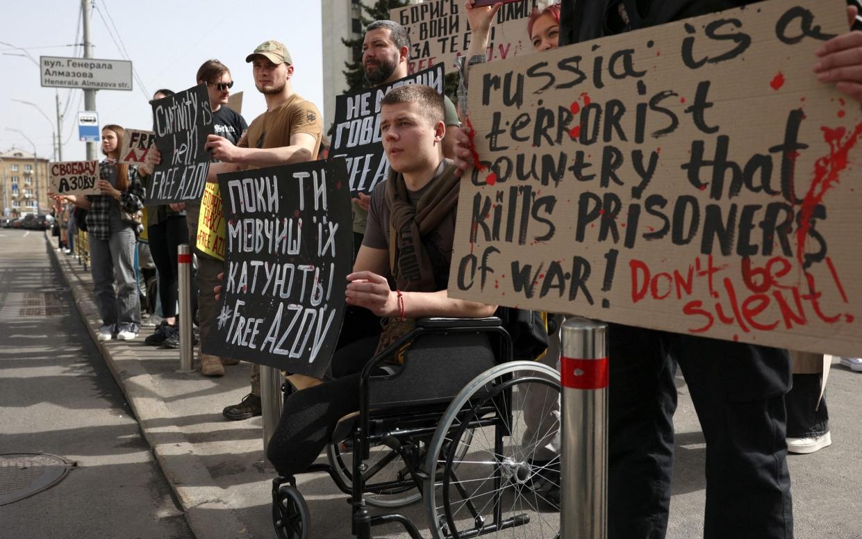 Veterans of the Russian-Ukrainian war, and relatives and friends of Ukrainian prisoners of war from the Azov Brigade  hold placards during the rally