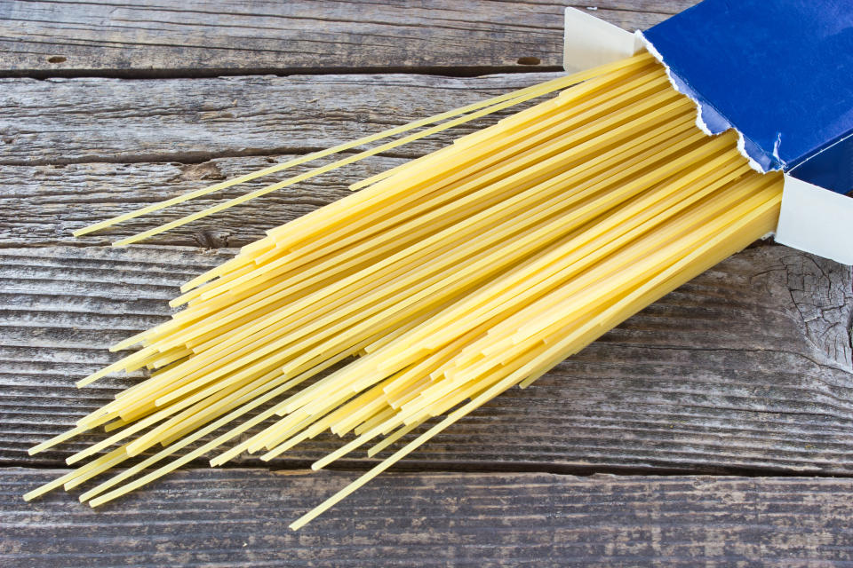 Spaghetti in cardboard box on wooden background.