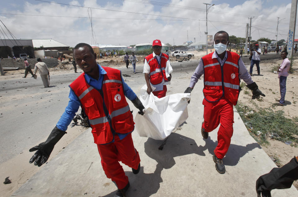 Somali Red Crescent workers carry away the body of a Somali civilian after an attack on a European Union military convoy in the capital Mogadishu, Somalia, Monday, Oct. 1, 2018. A Somali police officer says a suicide car bomber has targeted a European Union military convoy carrying Italian military trainers in the Somali capital Monday. (AP Photo/Farah Abdi Warsameh)