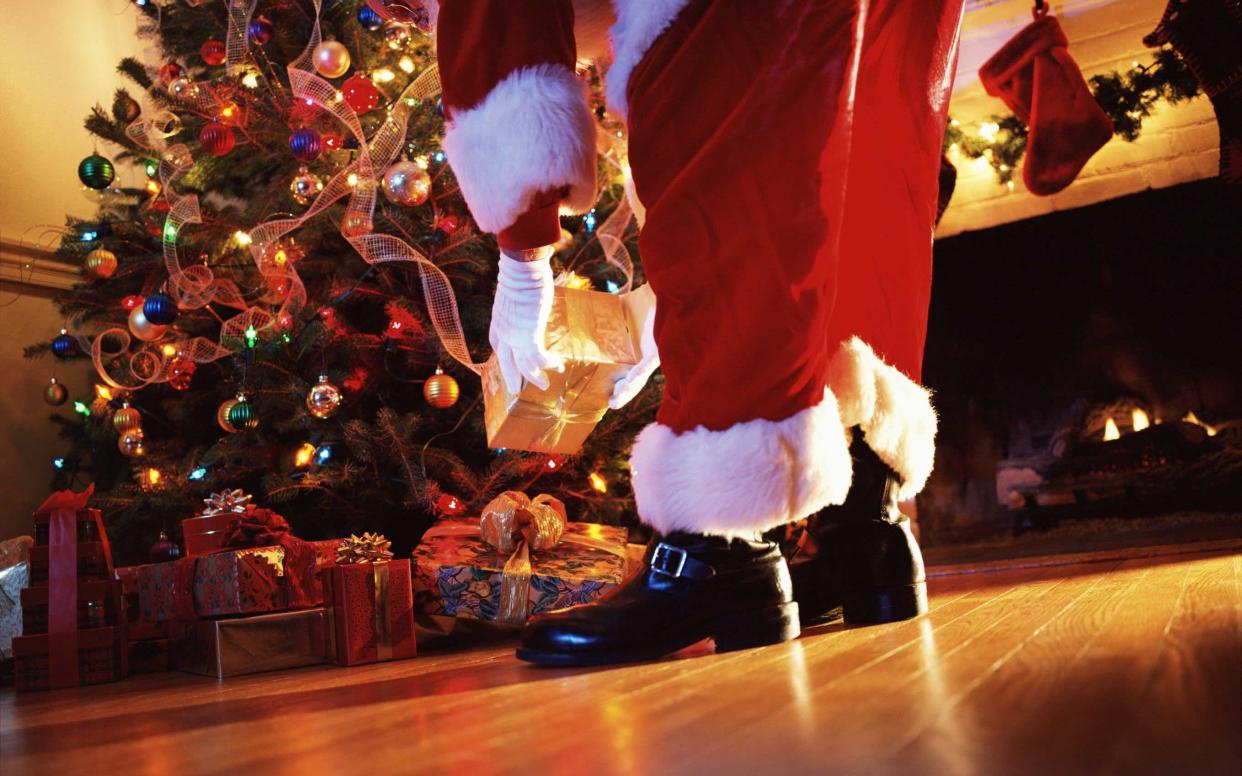 Santa Claus placing presents under a Christmas tree