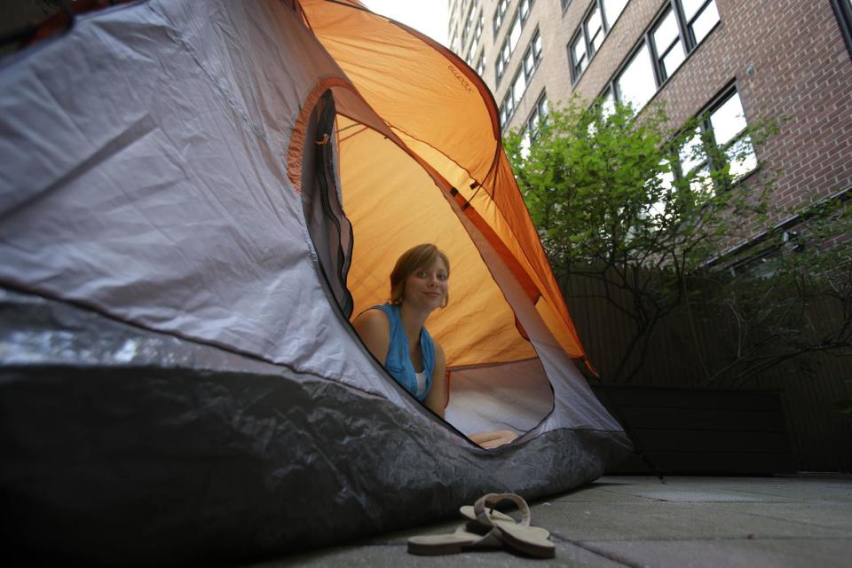 Kathleen Boyle poses for a picture in a tent on the patio of her room at the Affina Hotel in New York, Thursday, Aug. 15, 2013. A couple of New York City locales are offering an unusual option _ the chance to sleep outdoors, incredibly comfortably. It’s an urban take on “glamping,” where hotel comforts are taken outside. (AP Photo/Seth Wenig)