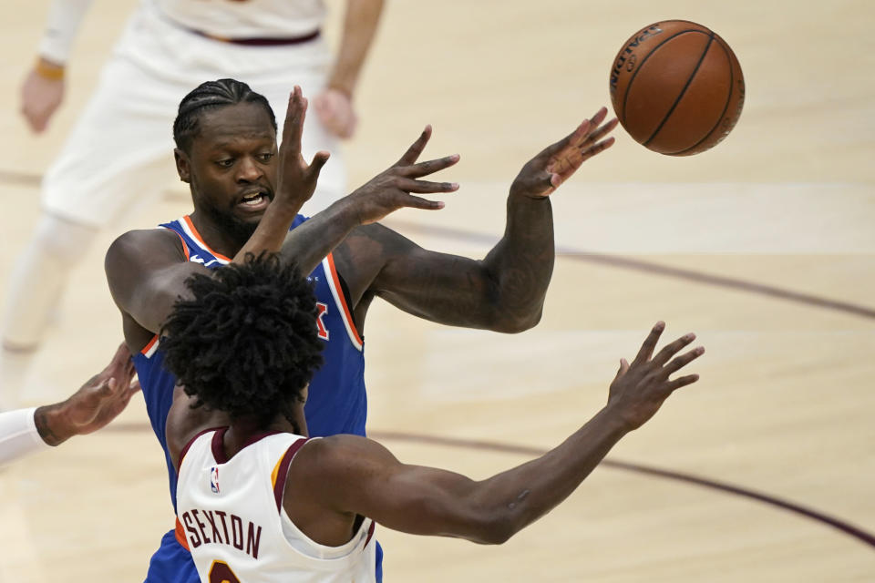 New York Knicks' Julius Randle, back, passes the ball away from Cleveland Cavaliers' Collin Sexton during the second half of an NBA basketball game Tuesday, Dec. 29, 2020, in Cleveland. The Knicks won 95-86. (AP Photo/Tony Dejak)