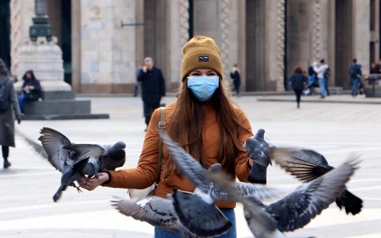 Pigeons circle around a tourist wearing a protective face mask in Duomo square in Milan, Italy - Paolo Sailmoirago/EPA-EFE/REX