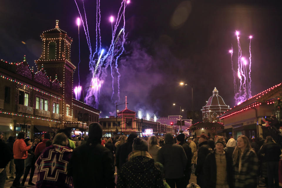 A crowd watches building lights come on as fireworks light up the sky during the Plaza Lighting Ceremony in Kansas City, Mo., Thursday, Nov. 28, 2019. The Country Club Plaza is a famous shopping district in Kansas City. This is the 90th year of the Plaza lights. (AP Photo/Orlin Wagner)