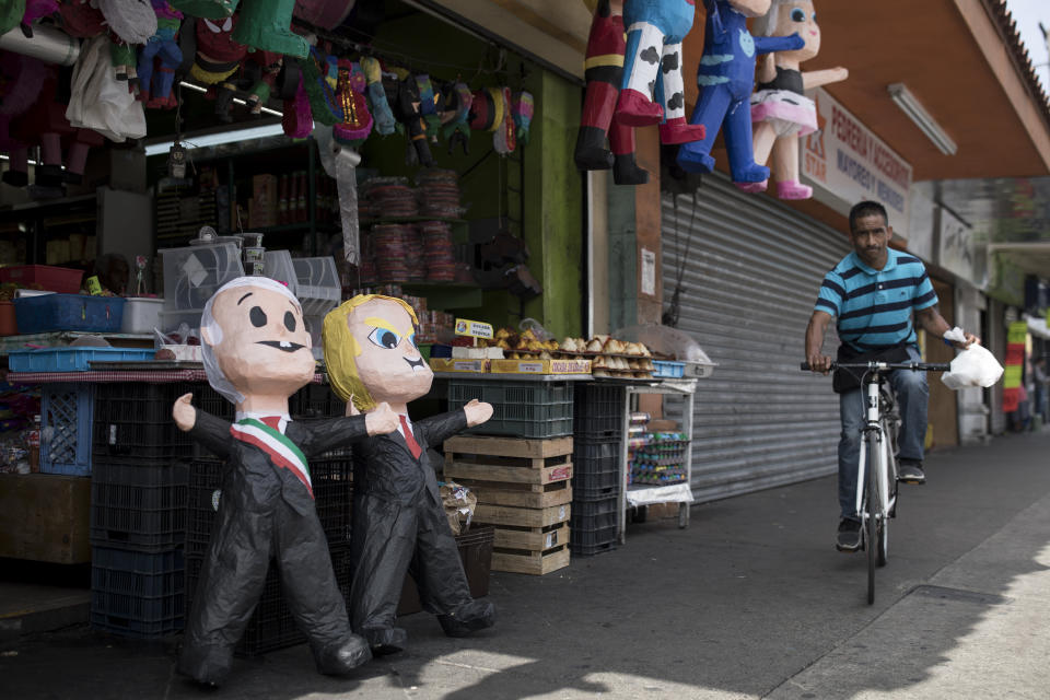 A man rides a bicycle next to a local market selling piñatas of Mexican President Andres Manuel Lopez Obrador and US President Donald Trump, in Tijuana, Mexico, Saturday, June 8, 2019. Mexican President Andres Manuel Lopez Obrador is to hold a rally in Tijuana even as President Trump has put on hold his plan to begin imposing tariffs on Mexico on Monday, saying the U.S. ally will take "strong measures" to reduce the flow of Central American migrants into the United States. (AP Photo/Hans-Maximo Musielik)