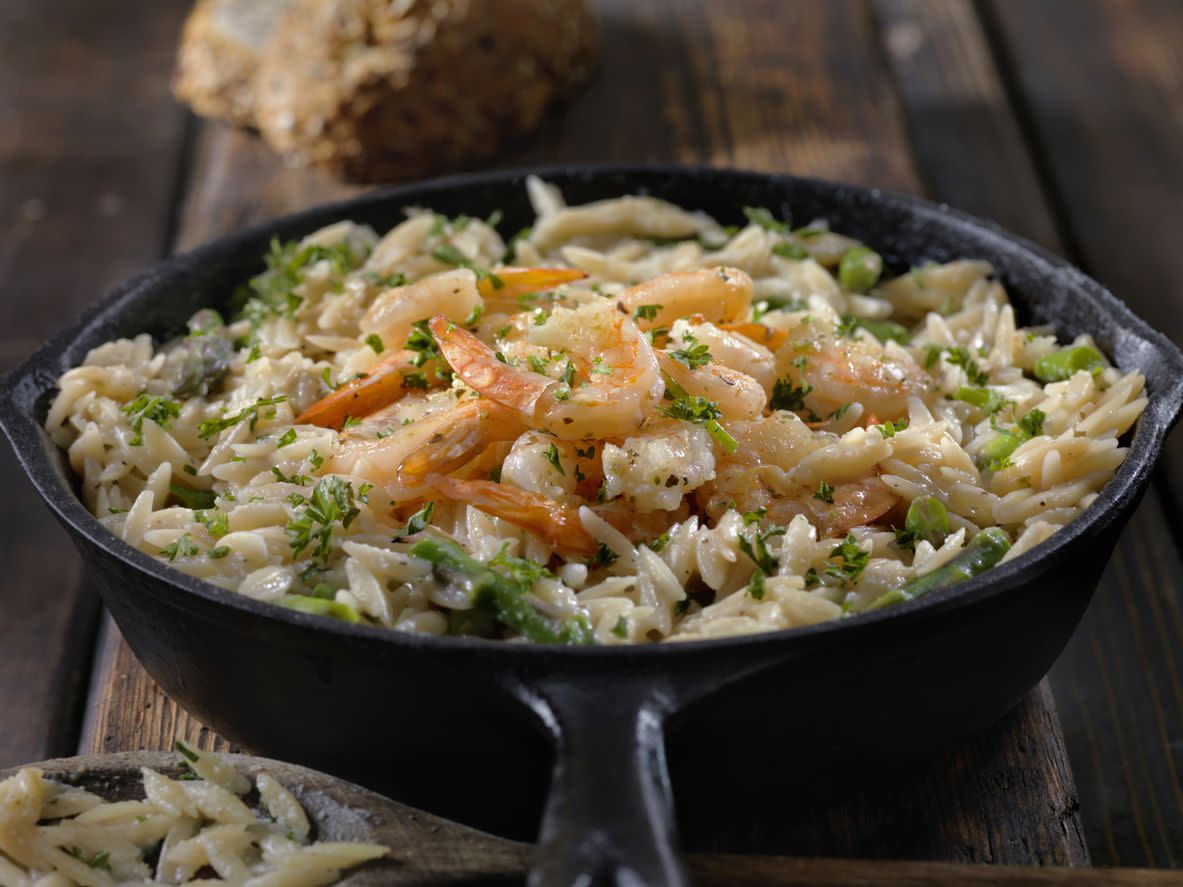 Creamy Parmesan Orzo with Shrimp and Asparagus in a cast iron pan on a rustic wooden table