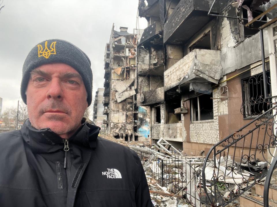 Steven Moore, founder of the Ukraine Freedom Project, stands in front of blow up apartment buildings in Borodyanka.