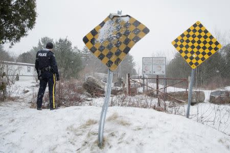 An Royal Canadian Mounted Police (RCMP) officer watches as a man is checked by U.S. border patrol before he crossed U.S.-Canada border into Hemmingford, Quebec, Canada March 2, 2017. REUTERS/Dario Ayala