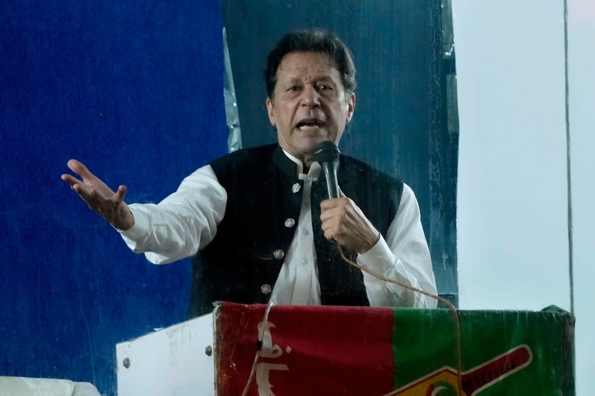 Protected by a bulletproof barrier, Imran Khan speaks during a rally in Lahore (AP)