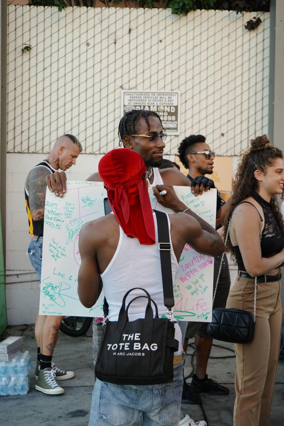 A person signing a poster held up in front of them.