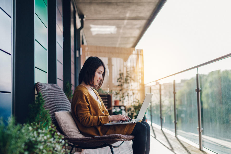 Young woman working on laptop in balcony