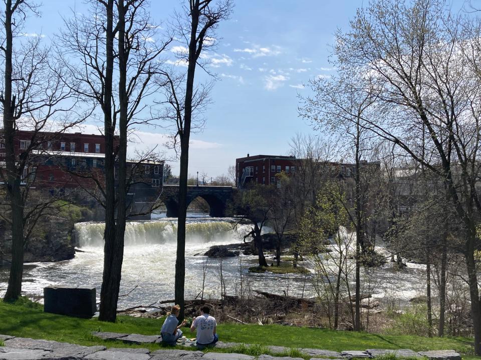 Picnickers sit along the Otter Creek in Middlebury on April 28, 2024.