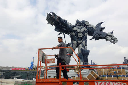 A worker rides on a cart in front of a giant robot statue at the Oriental Science Fiction Valley theme park in Guiyang, Guizhou province, China November 16, 2017. REUTERS/Joseph Campbell/Files