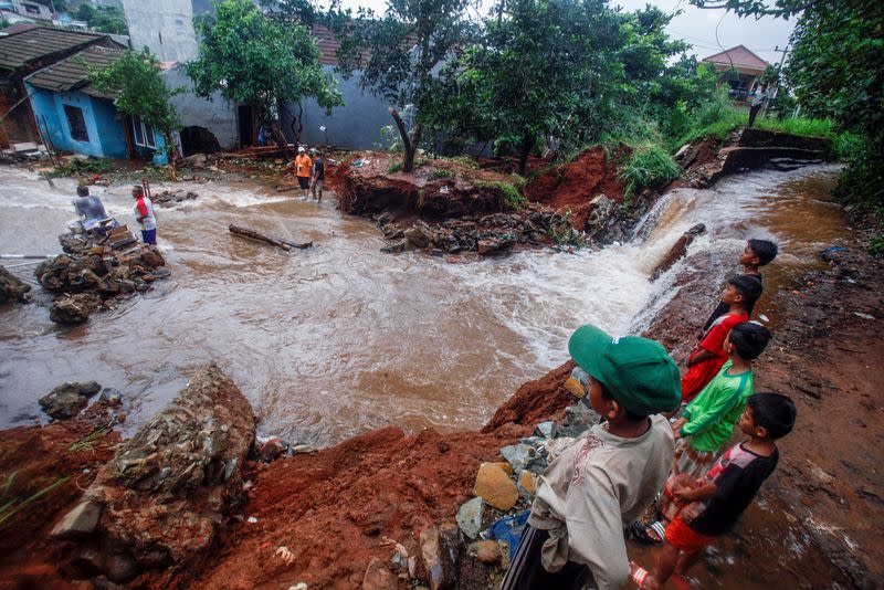 People look at a dam which collapsed after heavy rains in Bogor