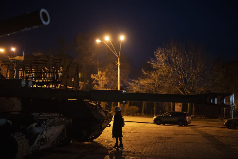 Una mujer parada frente a vehículos blindados y tanques rusos destruidos en el centro de Kiev
