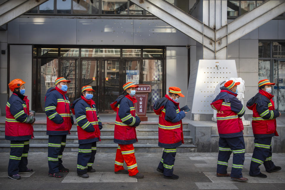 Urban street cleaners wearing face masks to protect against the spread of the coronavirus line up for mass COVID-19 testing in a central district of Beijing, Friday, Jan. 22, 2021. Beijing has ordered fresh rounds of coronavirus testing for about 2 million people in the downtown area following new cases in the Chinese capital. (AP Photo/Mark Schiefelbein)