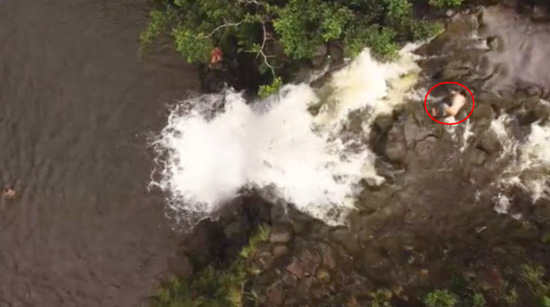 In this photo from Ms Lusano's drone her friend Sean can be seen climbing over wet rocks to reach the edge of the waterfall. Source: Renee Lusano