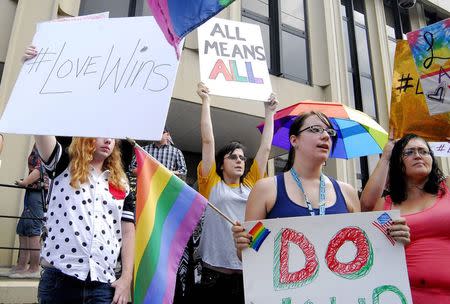 Demonstrators stand on the front steps of the federal building waving a rainbow flag in protest of Rowan County clerk Kim Davis' arrival to attend a contempt of court hearing for her refusal to issue marriage certificates to same-sex couples at the United States District Court in Ashland, Kentucky, September 3, 2015. REUTERS/Chris Tilley