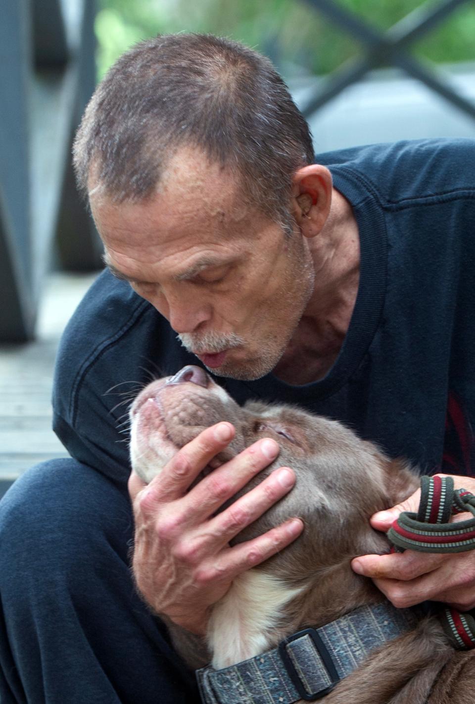 Jeffery Welborn of south Jackson, Miss., bends to kiss his dog Bella on Wednesday, May 8, 2024. Welborn has rescued 12 stray dogs. Out of the dozen, he’s kept two. He took the other 10 dogs to a no-kill shelter.