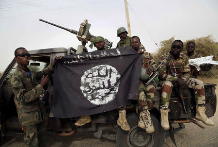 FILE PHOTO - Nigerian soldiers hold up a Boko Haram flag that they had seized in the recently retaken town of Damasak, Nigeria, March 18, 2015. REUTERS/Emmanuel Braun/File Photo