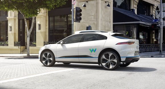 The new I-PACE SUV in white driving down a city street, with Waymo's 