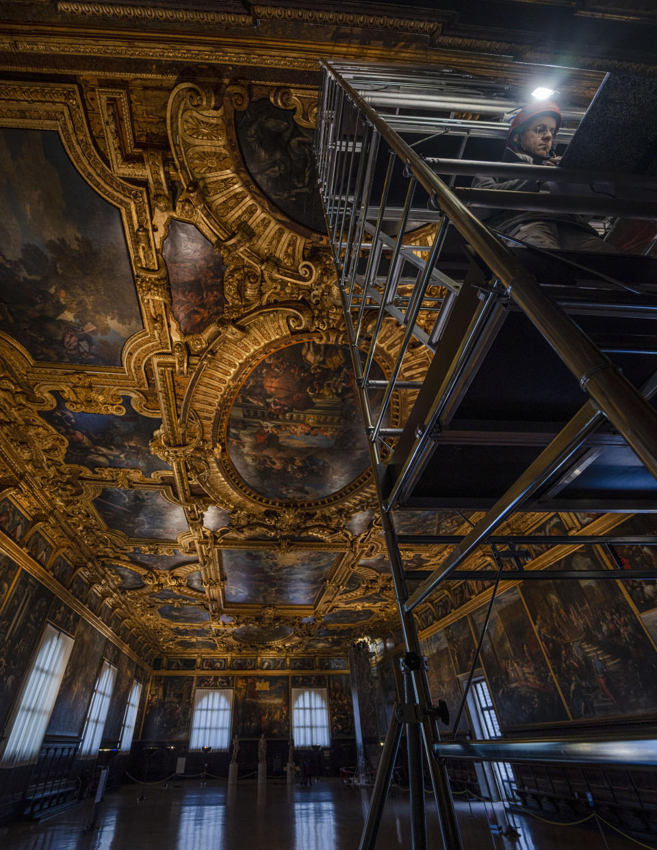 Restorer Alberto Marcon stands on a scaffolding to inspect the 7,45x24,65-meter oil on canvas 'Il Paradiso' completed in 1592 by Venetian painters Jacopo Robusti, also known as Tintoretto, and his son Domenico in the Maggior Consiglio Hall inside Palazzo Ducale in Venice, northern Italy, Wednesday, Dec. 6, 2022. The Doge's Palace, the heart of the political life of the Venetian Republic for centuries, is undergoing a major reconnaissance of its conservation status by the Fondazione Musei Civici of the municipality of Venice that includes the urgent restoration of its paintings and infrastructures, which is expected to be completed in the summer of 2023. (AP Photo/Domenico Stinellis)