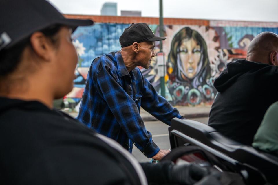 A man on a bicycle interacts with people on a cart.