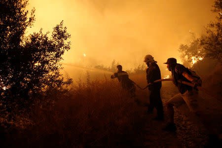 Firefighters try to extinguish a wildfire burning near the village of Kalamos, north of Athens, Greece, August 13, 2017. REUTERS/Costas Baltas