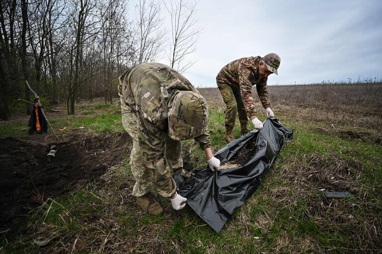 - Miembros del equipo de cooperación civil-militar ucraniano colocan en una bolsa de plástico el cuerpo de un soldado ruso en el norte de la región de Kharkiv el 11 de abril de 2023, en medio de la invasión rusa de Ucrania.