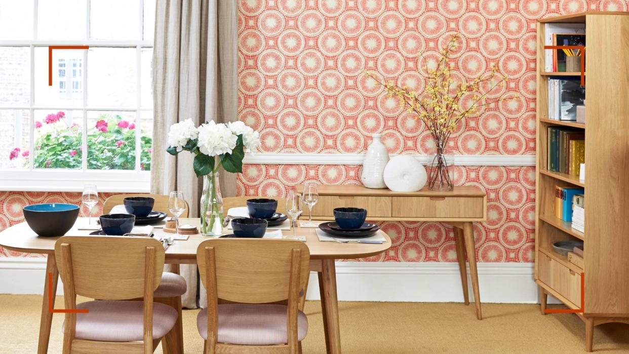  Living room with coral patterned wallpaper on wall with a window behind a dining table to support expert advice to answer can you paint over wallpaper. 