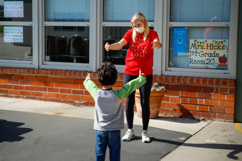 EL SEGUNDO, CA - JUNE 03: First Grade teacher Caitlin Hicks gives a "virtual hug" to Sid Solomon, 6 (7 in August), as she greets her students one final time, with social distance, picking up their years' work and see each other in person for the first time in months because of the coronavirus pandemic, at Center Street Elementary, in El Segundo, CA, on Wednesday, June 3, 2020. (Jay L. Clendenin / Los Angeles Times)