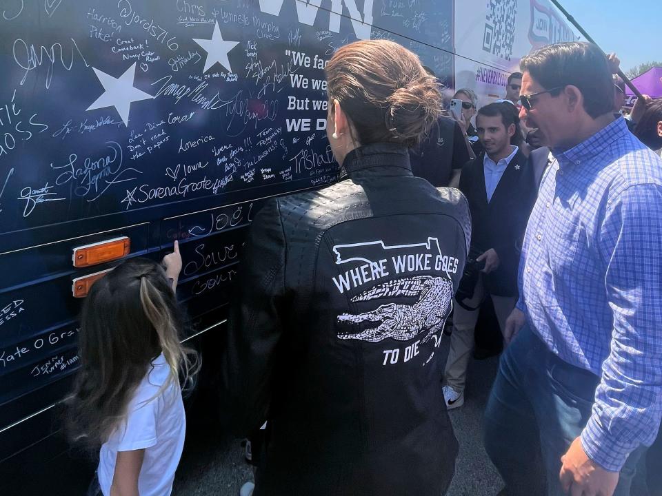 Casey DeSantis, center, the wife of presidential candidate Ron DeSantis, stands in front of the bus for her husband's super PAC, Never Back Down, at U.S. Sen. Joni Ernest's Roast and Ride, Saturday, June 3, 2023, in Des Moines, Iowa. (AP Photo/Hannah Fingerhut)