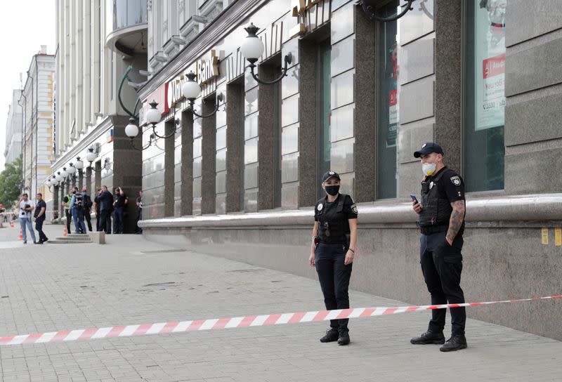 Police officers stand guard outside a building where an unidentified man reportedly threatens to blow up a bomb in a bank branch, in Kyiv