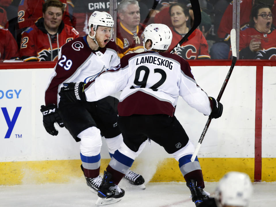 Colorado Avalanche center Nathan MacKinnon (29) celebrates his game-winning goal against the Calgary Flames with teammate Gabriel Landeskog (92) during overtime of an NHL hockey playoff game in Calgary, Alberta, Saturday, April 13, 2019. (Jeff McIntosh/The Canadian Press via AP)