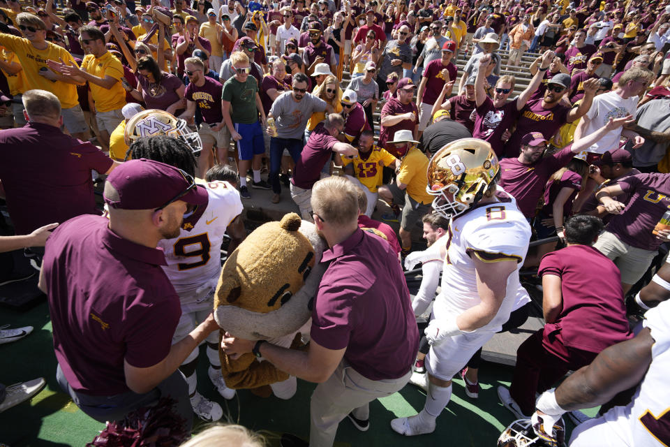 Minnesota mascot Goldy the Golden Gopher, front center, is helped up after fans collapsed the fence around the field and trapped the mascot after an NCAA college football game against Colorado, Saturday, Sept. 18, 2021, in Boulder, Colo. Minnesota won 30-0. (AP Photo/David Zalubowski)