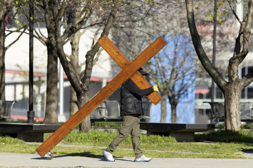 Dan Beazley from Michigan walks with a cross before a vigil held for victims of The Covenant School shooting on Wednesday, March 29, 2023, in Nashville, Tenn. (AP Photo/Wade Payne)