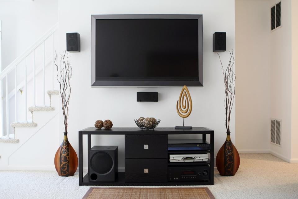 Tv hanging on the wall above a modern media cabinet in a modern living room