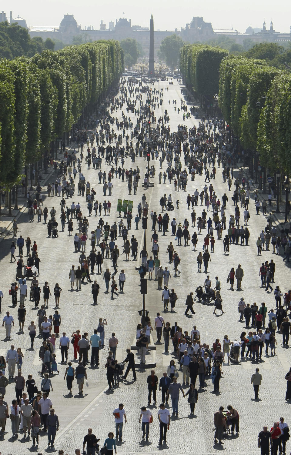 FILE- Visitors walk towards planted fields on the Champs Elysees near the "Place de la Concorde" (Concorde's square) monument in Paris, Sunday, May 23, 2010. Some 4,400 of the world's best athletes, parading down France's most famous boulevard with their prosthetic limbs, mobility chairs and stories of adversities overcome, to a grand celebration of their prowess and sports on the Paris square where the French revolutionaries of 1789 chopped off heads. (AP Photo/Jacques Brinon, File)