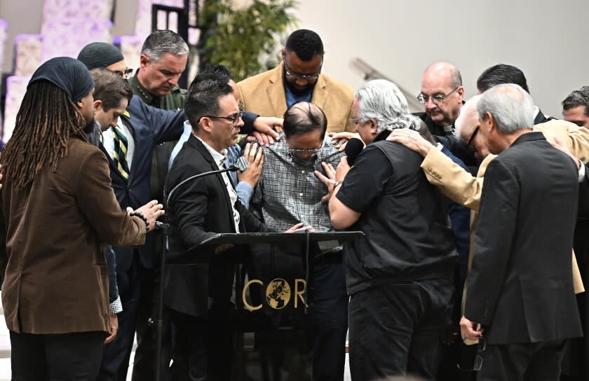 Irvine, California May 16, 2022-Officials pray around former pastor Billy Chang, center, who helped subdue the shooter, tries to hold back his emotions after speaking during a vigil at Christ Our Redeemer Church in Irvine Monday. (Wally Skalij/Los Angeles Times)