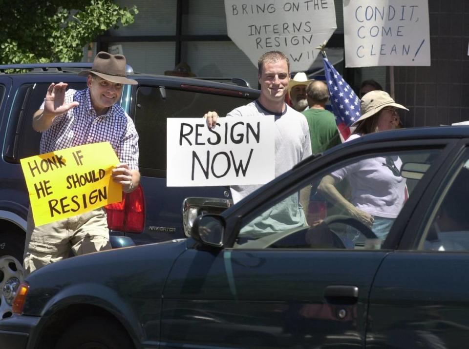 In this July 28, 2001, photo, Modesto residents Russ Heffner at left and Jared Wise look for support from passing drivers on 16th street in front of Congressman Gary Condit’s office at a protest by freedom.com that called for Condit’s resignation.