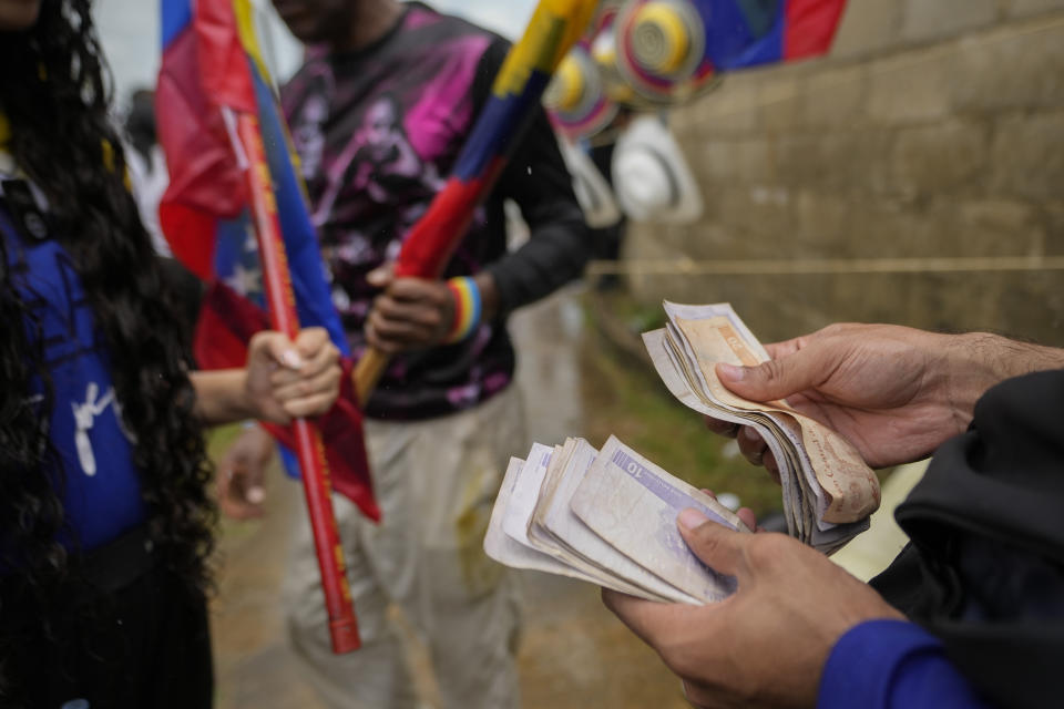 Un simpatizante cuenta bolívares para comprar una bandera nacional en un acto de campaña de la oposición presidencial del candidato Edmundo González, en Maturín, Venezuela, el sábado 20 de julio de 2024. Venezuela tiene elecciones presidenciales el domingo 28 de julio. (AP Foto/Matías Delacroix)