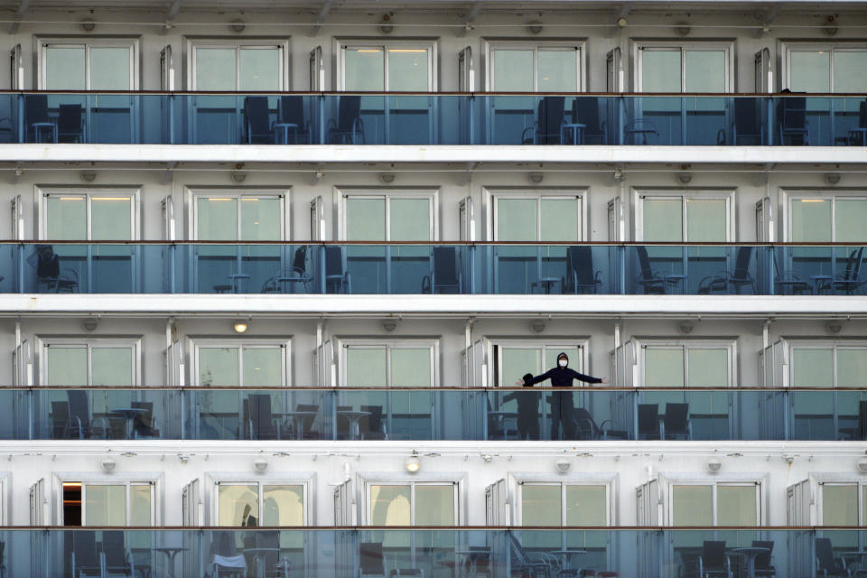 A passenger stands on the balcony of the cruise ship Diamond Princess anchored at the Yokohama Port in Yokohama, near Tokyo Friday, Feb. 7, 2020. Japan on Friday reported 41 new cases of a virus on a cruise ship that's been quarantined in Yokohama harbor while the death toll in mainland China rose to 636, including a doctor who got in trouble with authorities in the communist country for sounding an early warning about the disease threat. (AP Photo/Eugene Hoshiko)