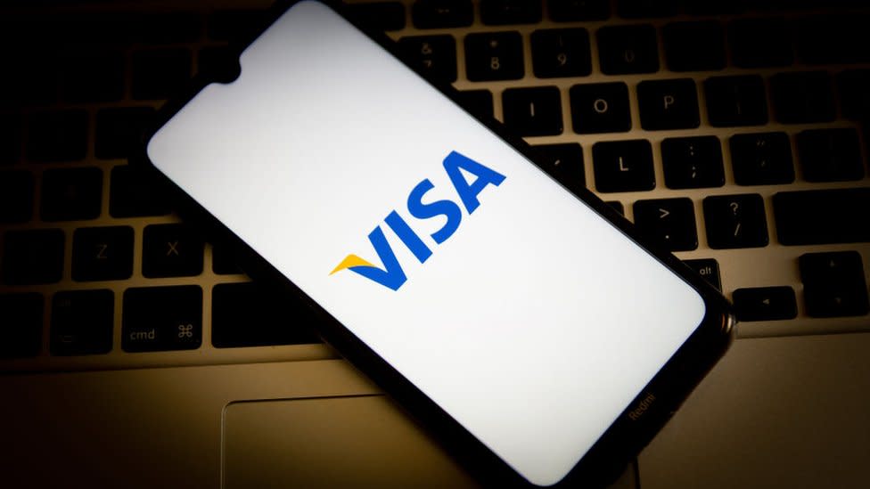 Un teléfono con el logo de Visa sobre el teclado de una computadora.