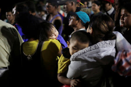 Children sleep on the arms of their parents along other Hondurans fleeing poverty and violence, as they move in a caravan toward the United States, in San Pedro Sula, Honduras October 13, 2018. REUTERS/Jorge Cabrera