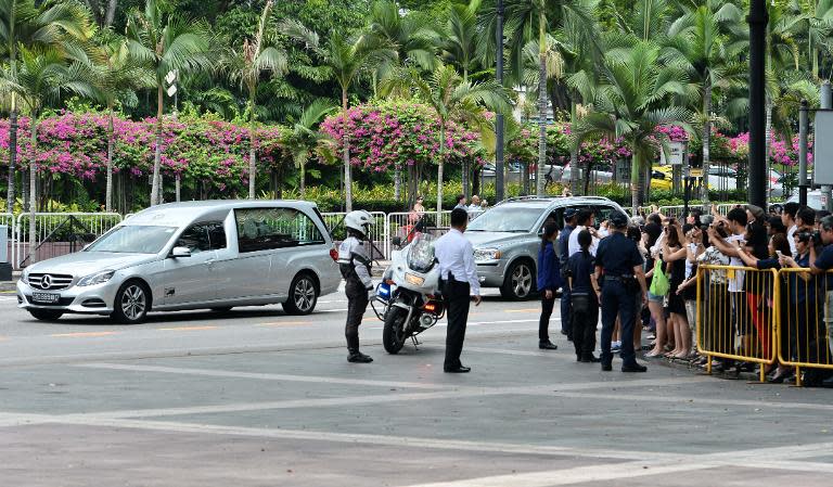 A crowd watches as a hearse carrying Lee Kuan Yew's remainds arrives at Istana presidential palace