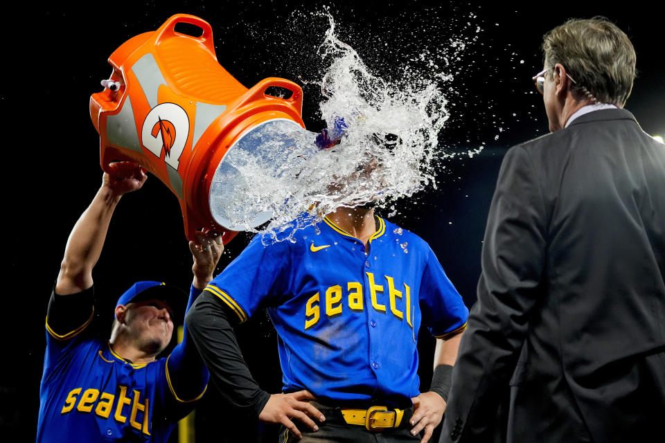 Seattle Mariners' Josh Rojas is doused by teammate Ty France, left, during an interview after the team's win over the Arizona Diamondbacks in a baseball game Friday, April 26, 2024, in Seattle. (AP Photo/Lindsey Wasson)