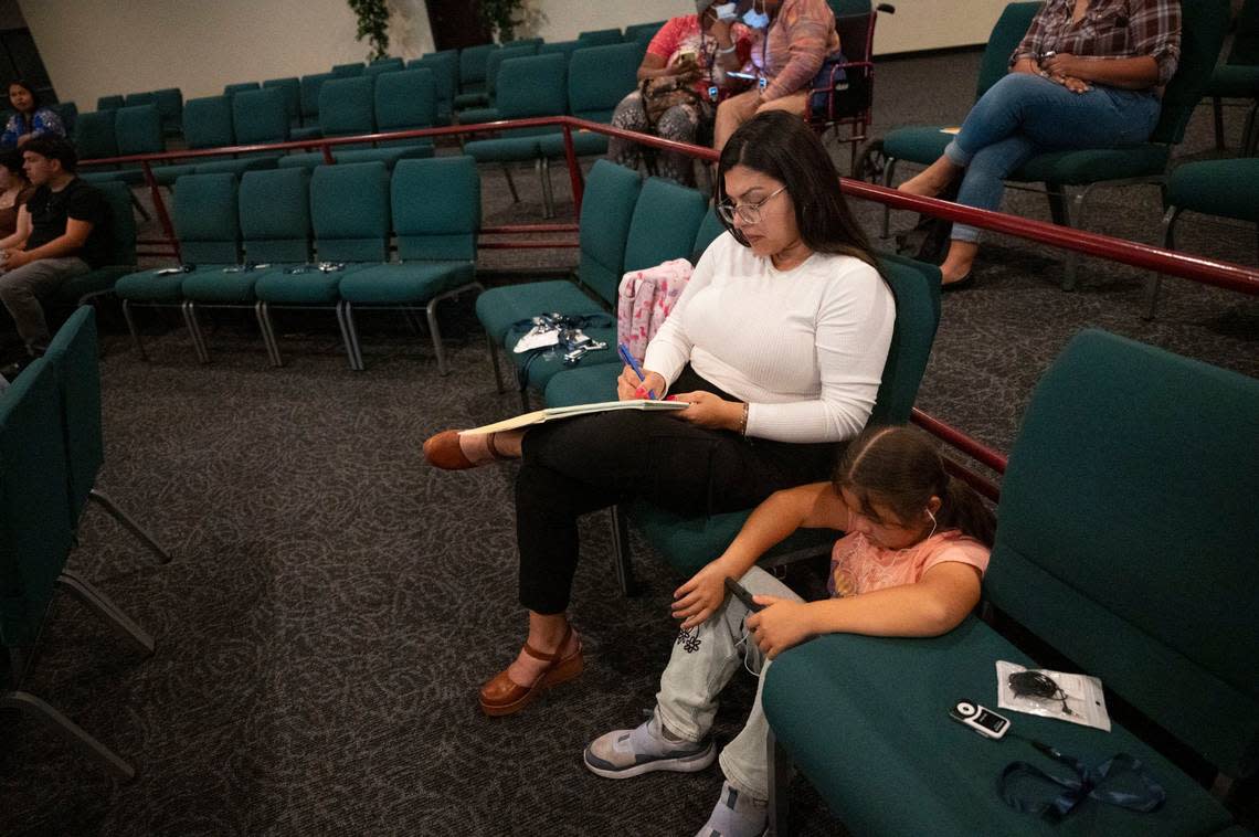 Prisila Isais takes notes as her daughter Isabel, 8, a Sacramento City Unified School District student, watches a video on her phone while attending a Sacramento ACT town hall meeting about community schools at South Sacramento Christian Center on April 12. Lezlie Sterling/lsterling@sacbee.com