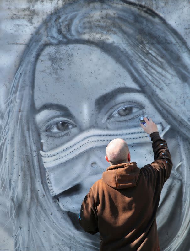 Artist Perez paints a graffiti of a cashier to pay tribute to essential workers in Gland