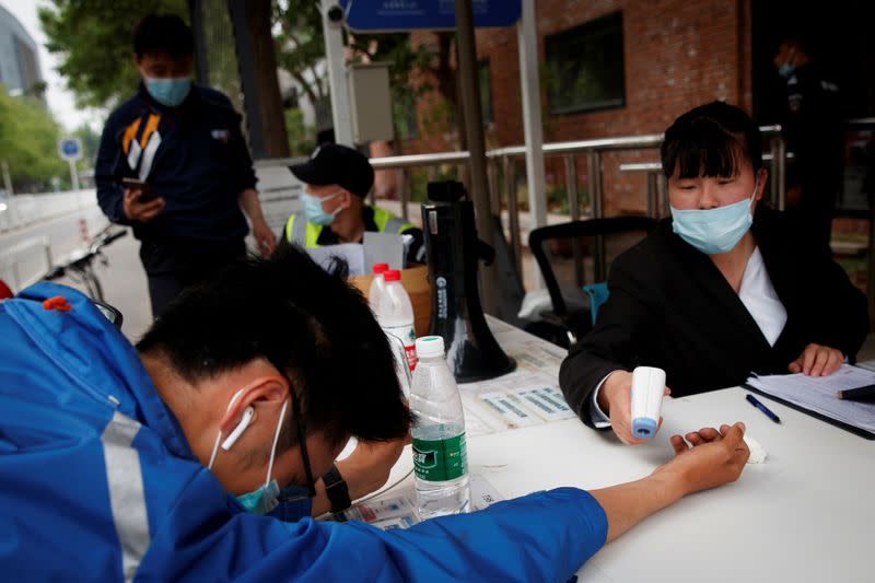 Delivery driver has his temperature checked after presenting the status of his health app in Beijing