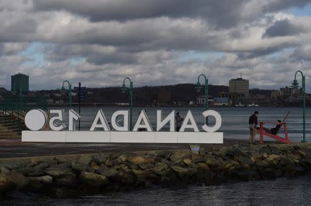 People pose next to the Canada 150 sign that was moved off its mooring from the storm surge during Storm Grayson in Halifax, Nova Scotia, Canada January 5, 2018. REUTERS/Darren Calabrese